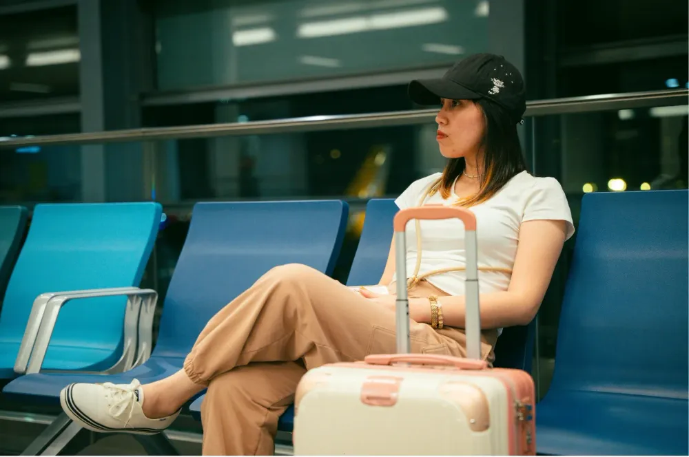 A traveler waiting in an airport terminal with a suitcase.
