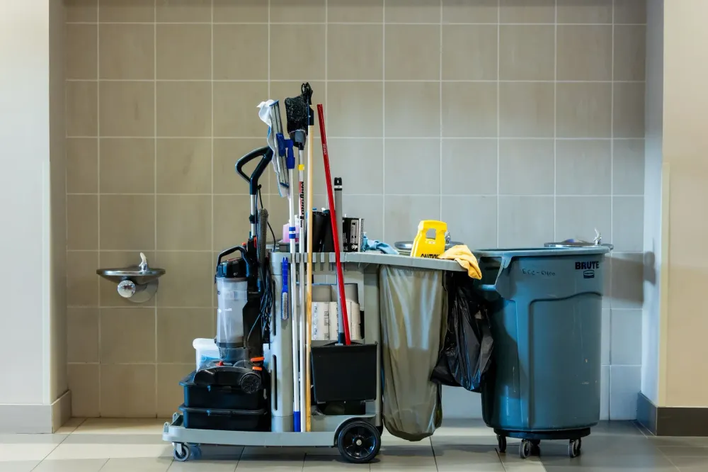 A janitorial cart stocked and ready in a tiled corridor.